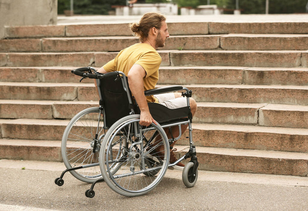 Νεαρός σε αναπηρική καρέκλα κοντά σε σκάλες - Φωτογραφία, εικόνα