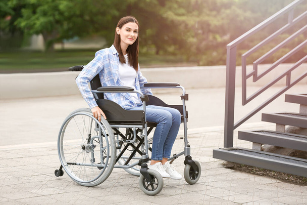 Dışarıda merdivenlerin yanında tekerlekli sandalyede genç bir kadın var. - Fotoğraf, Görsel