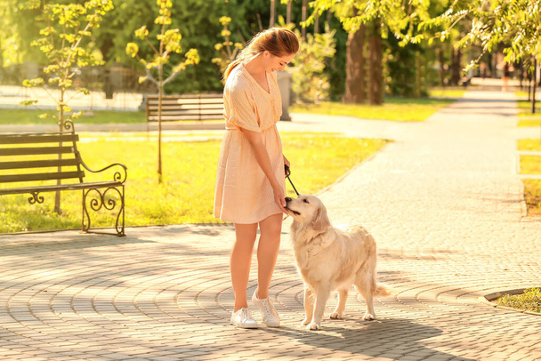 Молодая женщина с милой собакой гуляет в парке - Фото, изображение