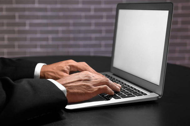 Бизнесмен работает за компьютером за столом в темной комнате - Фото, изображение