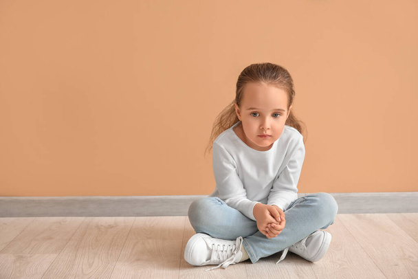 Sad little girl with autistic disorder sitting near color wall - Foto, imagen