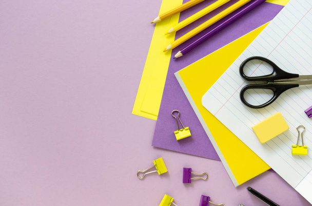 Colocação plana de materiais escolares amarelos e lilás em um fundo de cor. Espaço para texto
 - Foto, Imagem
