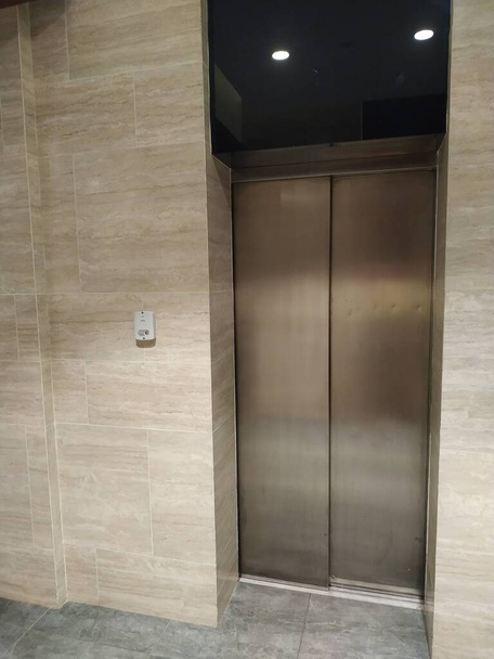 Порожній сучасний ліфт або ліфт з металевими дверима, які відкриті в будівлі з освітленням
. - Фото, зображення