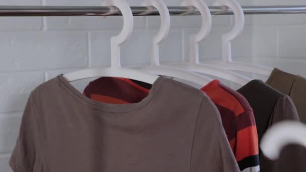 A woman takes clothes from a hanger. Women's clothing hangs on a hanger. Buy clothes. Choose clothes for a trip. Clean up the closet, dressing room. Clearing the Cabinet. Basic wardrobe, minimalism. - Footage, Video