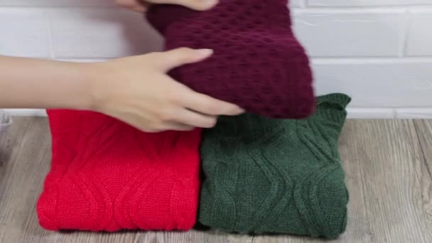 Neatly folded winter clothes. Folding sweaters in a pile. Cozy sweaters are lying in a pile. A female hand on stacks warm sweaters in pile. Female stacking the warm sweaters into the pile. - Footage, Video