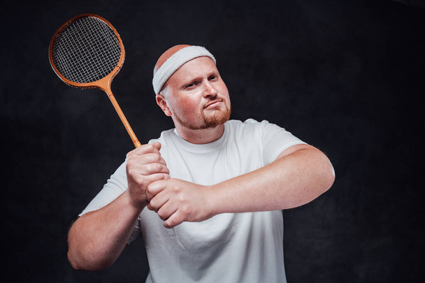 A man in white sportswear holds a rocket with two hands, looking at the camera - Photo, Image
