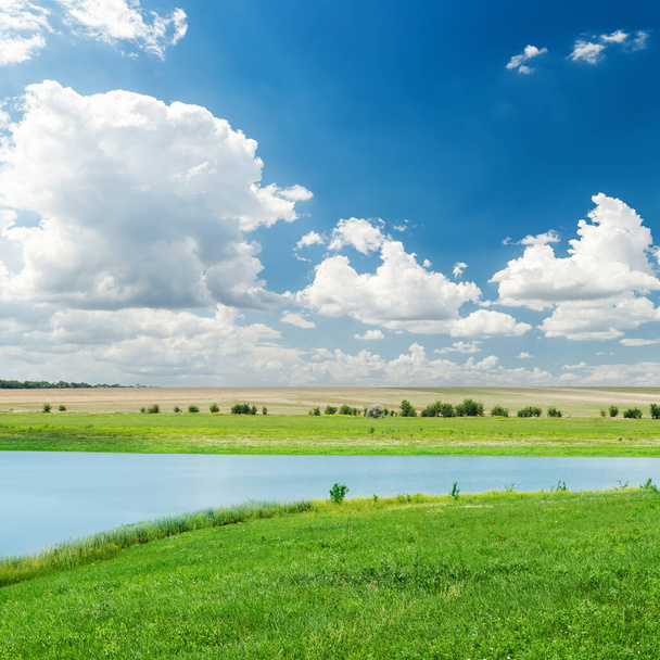 river in green grass and clouds over it in deep blue sky - Photo, Image
