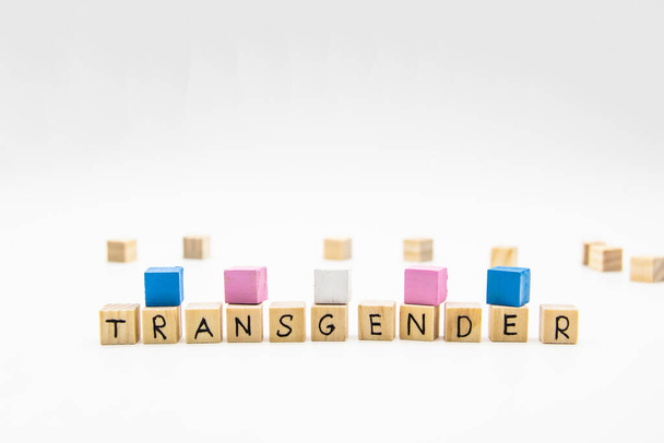 Uma palavra letras transgênero feitas de cubos de madeira e bandeira transgênero em fundo branco. Ilustração conceitual lésbica, gay, bissexual e transgênero com espaço de cópia
 - Foto, Imagem