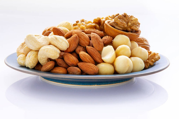 Voedzame gemengde noten op het bord, walnoten, amandelen, cashewnoten, macadamianoten - Foto, afbeelding