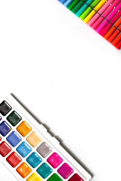 A palette of color watercolors with brushes and markers on a white background with space for text. Creative classes with children at home and at school, art master class, development. Desktop -flatlay - Foto, imagen