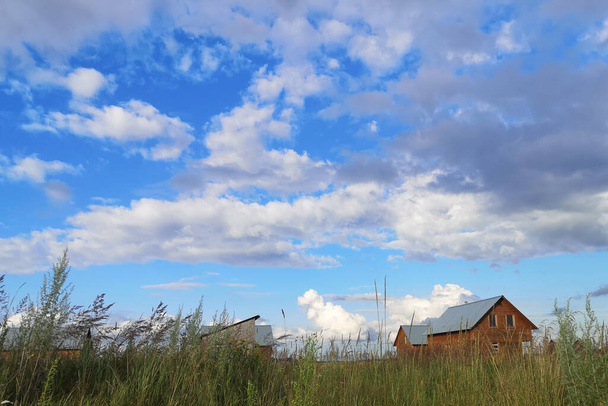 Large white clouds in the blue sky above a village in Russia. - Foto, Imagem