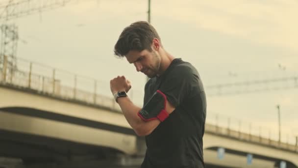 A slim man is doing exercises stretching his arms outdoors - Materiał filmowy, wideo