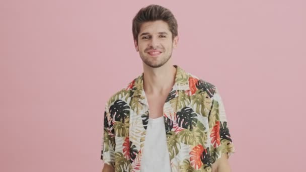 A handsome man is posing to the camera standing isolated over pink background - Séquence, vidéo