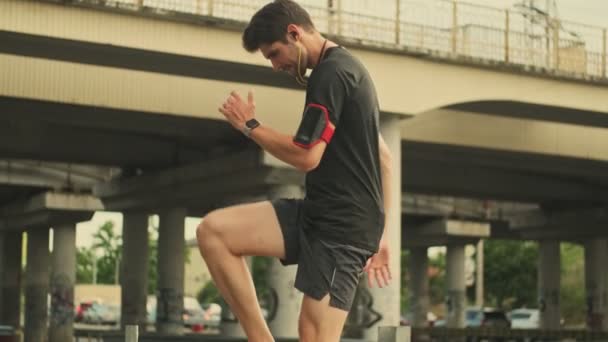 A focused man is training outside in the city near bridge - Filmati, video