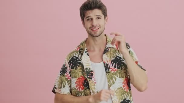 A cheerful young man is dancing isolated over pink background - Metraje, vídeo