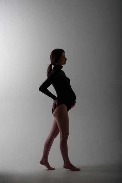 Young beautiful pregnant woman in black bodysuit. - Fotografie, Obrázek