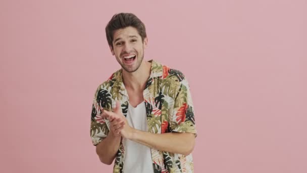 A emotional happy young man is applauding isolated over a pink background - Video