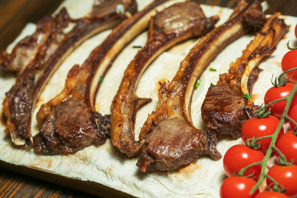 Côtes de rechange grillées épicées d'un barbecue d'été servi avec un piment fort et des tomates fraîches sur une vieille planche à découper vintage en bois. - Photo, image