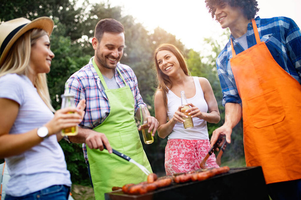 Small group of friends drinking alcohol and having a meal at barbecue party - Foto, imagen