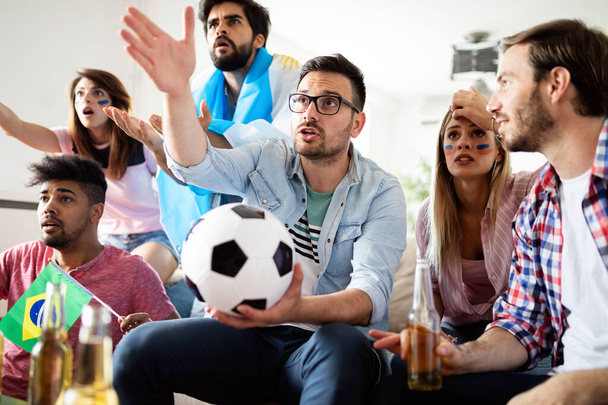 Nuori ryhmä jalkapallofanit pettynyt ja onnellinen katsomassa jalkapallo peli sohvalla. - Valokuva, kuva