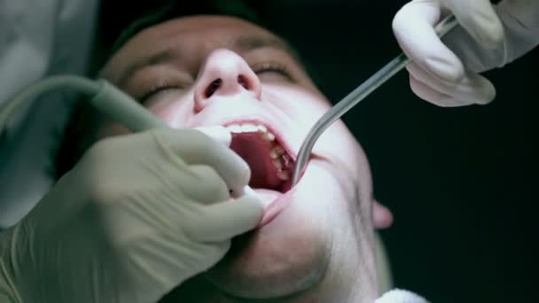 Tandarts tot vaststelling van de tanden terwijl assistent SIP's het speeksel - Video