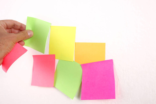 male hand put a blank paper sticky note on the wall with copy space for your text - Foto, Imagen