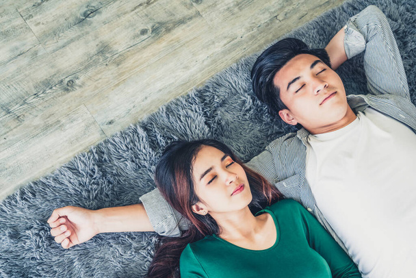 Feliz pareja asiática acostados juntos en la alfombra en el piso de la sala de estar. Amor relación y concepto de estilo de vida
. - Foto, imagen