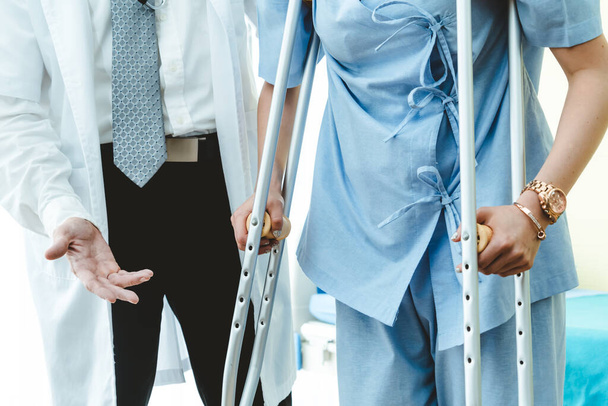 Arzt versorgt Patientin auf Krücken im Krankenhaus Physiotherapeut und Konzept zur Genesung von Beinverletzungen. - Foto, Bild
