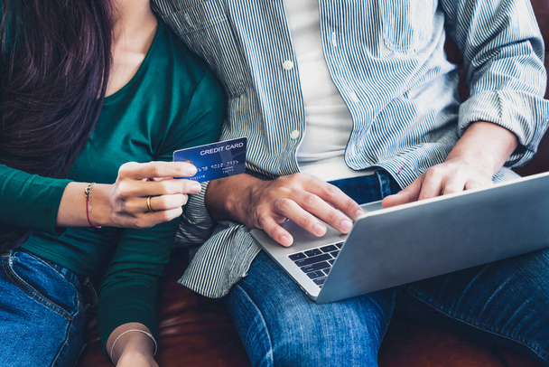 Young couple use credit card for online shopping on internet website at home. Number on the credit card is mock up. No personal information shown on the credit card. Online business shopping concept. - Photo, Image