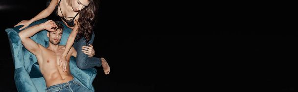 Vízszintes termés női melltartó megható izmos törzs jóképű barátja karosszék elszigetelt fekete  - Fotó, kép