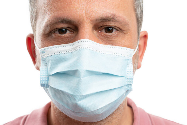 Close-up of man face with medical surgical disposable mask as influenza flu virus spreading concept - Foto, immagini