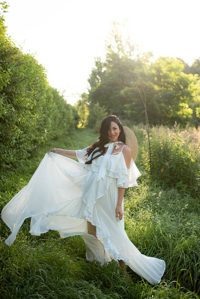 Pregnant woman posing in a white dress on a background of nature. - Photo, Image