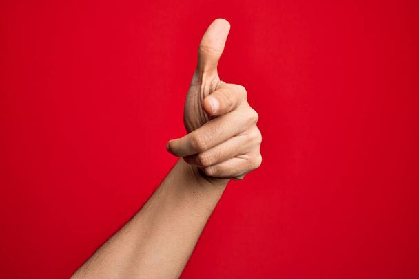 Hand of caucasian young man showing fingers over isolated red background pointing forefinger to the camera, choosing and indicating towards direction - Photo, Image