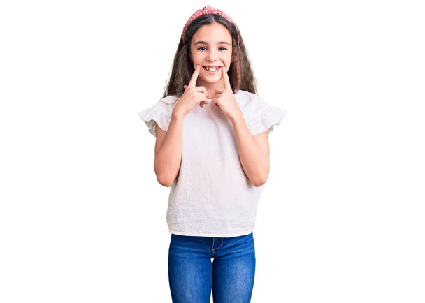 Cute hispanic child girl wearing casual white tshirt smiling with open mouth, fingers pointing and forcing cheerful smile  - Foto, immagini