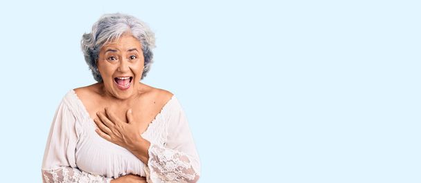 Donna anziana con i capelli grigi indossa stile bohemien sorridente e ridente forte perché divertente scherzo pazzo con le mani sul corpo.  - Foto, immagini