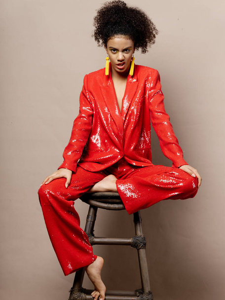 Woman in shiny red suit decoration bright makeup curly dark hair  - Photo, Image