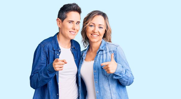 Couple de femmes portant des vêtements décontractés pointant les doigts vers la caméra avec un visage heureux et drôle. bonne énergie et vibes.  - Photo, image
