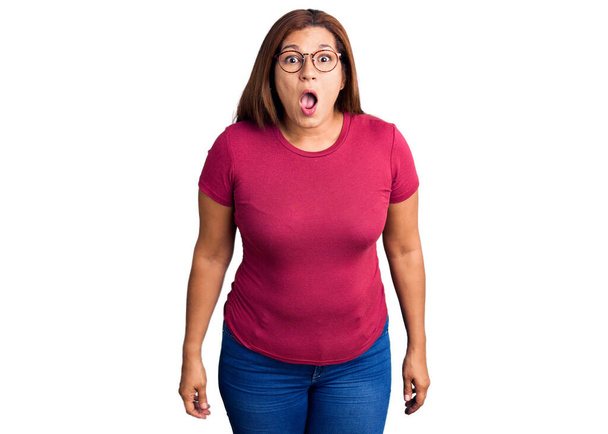 Mujer latina de mediana edad vistiendo ropa casual y gafas asustada y sorprendida con la boca abierta para sorpresa, cara de incredulidad
  - Foto, imagen