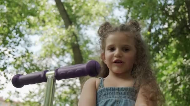 A beautiful young girl looks at the camera and speaks. Summer park. - Filmagem, Vídeo
