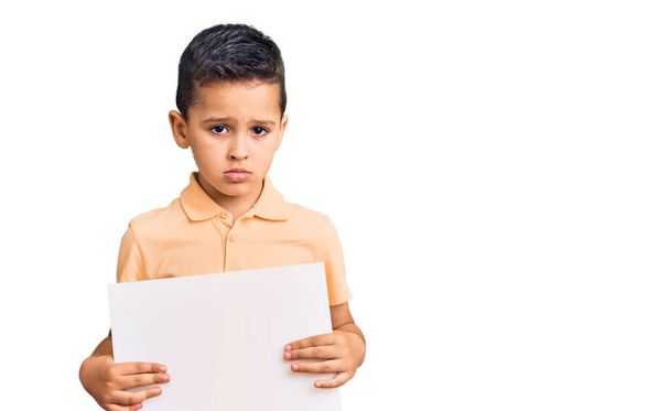 Μικρό χαριτωμένο παιδί αγόρι κρατώντας χαρτονένιο πανό με κενό χώρο σκέψης στάση και νηφάλια έκφραση που αναζητούν αυτοπεποίθηση  - Φωτογραφία, εικόνα