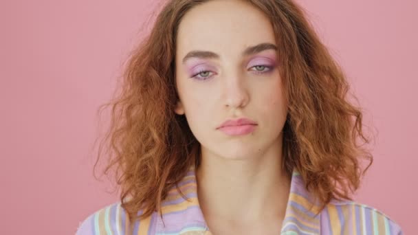 A calm young woman is opening her eyes standing isolated over a pink background in studio - Felvétel, videó
