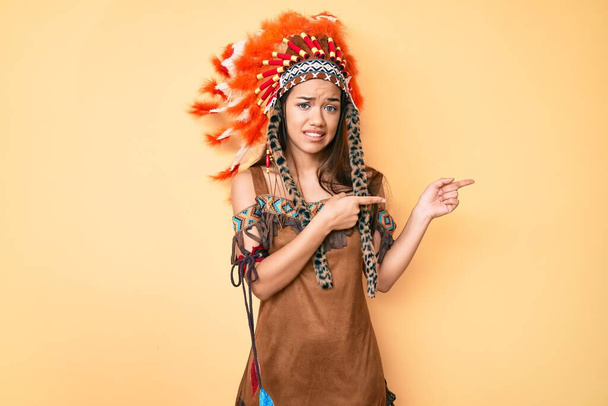 Menina latina bonita jovem vestindo traje indiano apontando para o lado preocupado e nervoso com as duas mãos, preocupado e expressão surpresa
  - Foto, Imagem