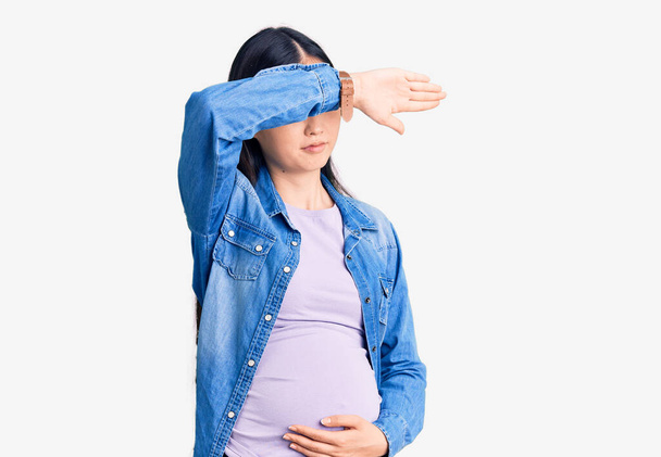 Молода вродлива жінка, вагітна вагітною, очікує, що малюк закриє очі руками, виглядає серйозною і сумною. Безпомічні, приховані і відкинуті поняття  - Фото, зображення