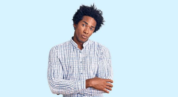 Schöner afrikanisch-amerikanischer Mann mit Afro-Haaren in lässiger Kleidung, skeptisch und nervös, ablehnender Gesichtsausdruck mit verschränkten Armen. Negative Person.  - Foto, Bild