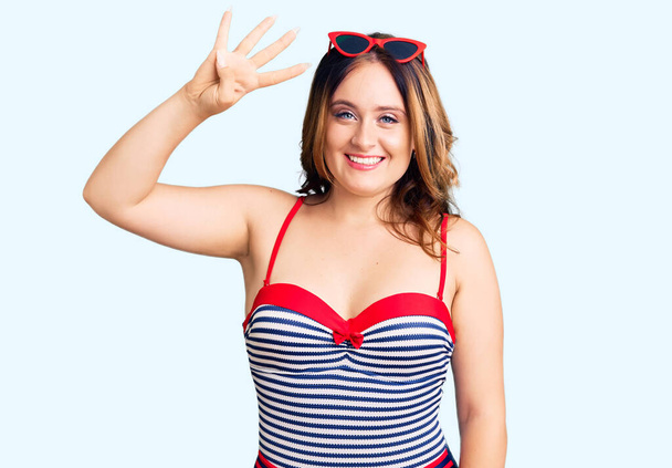 Young beautiful caucasian woman wearing swimwear showing and pointing up with fingers number four while smiling confident and happy.  - Photo, Image