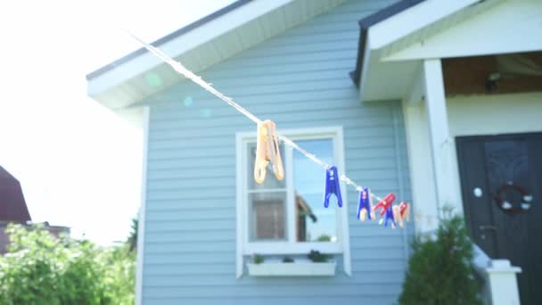 wasknijpers hangen aan een touwtje voor het huis in de zon - Video