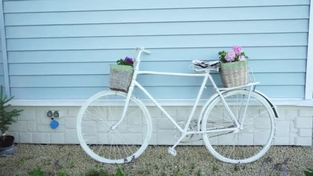 Rower Retro z dwoma koszami kwiatów na tle niebieskiego domu. Wystrój ogrodu w stylu Prowansji - Materiał filmowy, wideo