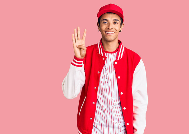 自信と幸せな笑顔ながら、若いアフリカ系アメリカ人の男は、野球の制服を着て指の数4で示すと指摘します.  - 写真・画像