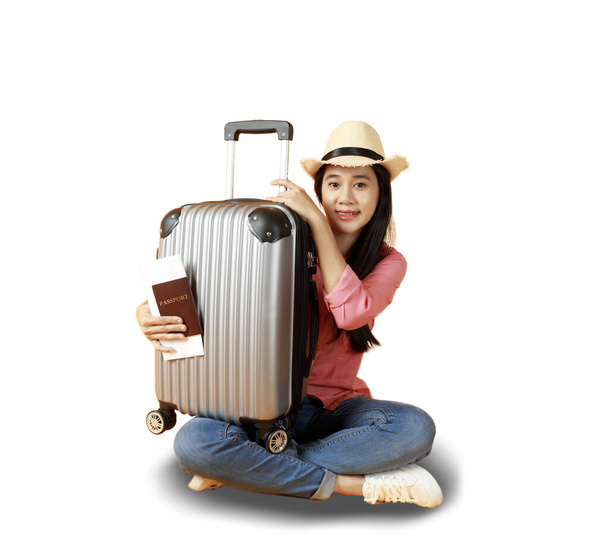 Ασιάτισσες γυναίκες μακριά μαλλιά φορούν Straw καπέλο, κάθεται στο χέρι κρατώντας το βιβλίο διαβατηρίων και ταξιδιωτική τσάντα με χώρο αντίγραφο.. Νεαρό κορίτσι έτοιμο να ταξιδέψει με τη βαλίτσα και το διαβατήριο σε λευκό φόντο. Καλοκαιρινές διακοπές. - Φωτογραφία, εικόνα