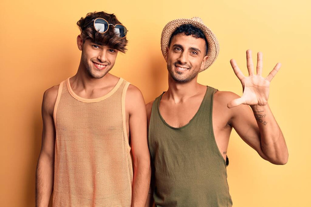 Young gay couple wearing summer clothes showing and pointing up with fingers number five while smiling confident and happy.  - Fotoğraf, Görsel